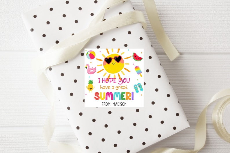 Peut inclure: Une &eacute;tiquette cadeau color&eacute;e avec un soleil souriant portant des lunettes de soleil et entour&eacute; d'ic&ocirc;nes d'&eacute;t&eacute; comme un flamant rose, une past&egrave;que, une glace et des tongs. Le texte dit "J'esp&egrave;re que vous avez un bel &Eacute;T&Eacute; ! De : Madison".