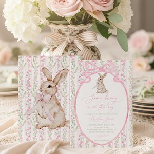 May include: Two baby shower invitations with a bunny theme. The invitations feature a watercolor illustration of a bunny with a pink bow. The text "Some bunny is on the way" is written in pink script.