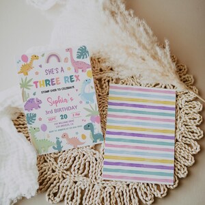 May include: A colourful dinosaur-themed birthday invitation with a rainbow, a dinosaur, and the text "She's a Three Rex" and "Sophia's 3rd Birthday".
