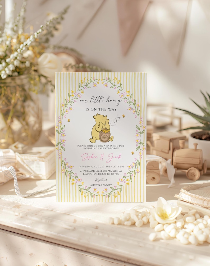 May include: A baby shower invitation with a Winnie the Pooh theme. The card features a yellow and white striped background, floral accents, and the text "our little hunny is on the way." The invitation includes the names Sophie & Jack.