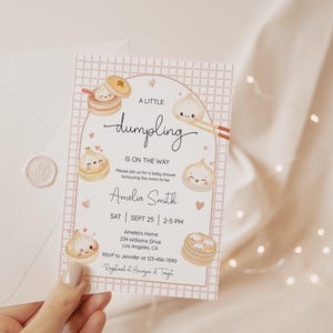 May include: A baby shower invitation card with a dumpling theme. The card features illustrations of dumplings and the text "A Little Dumpling Is On The Way". The card is held with a white envelope and a wax seal.