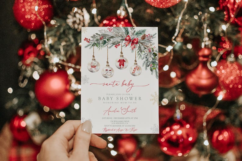 May include: A baby shower invitation with a Christmas theme. The invitation features a festive design with hanging ornaments, greenery, and a red bow. The text reads "santa baby" and includes details for the event.