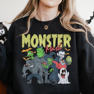 a woman sitting on a couch wearing a black monster sweatshirt