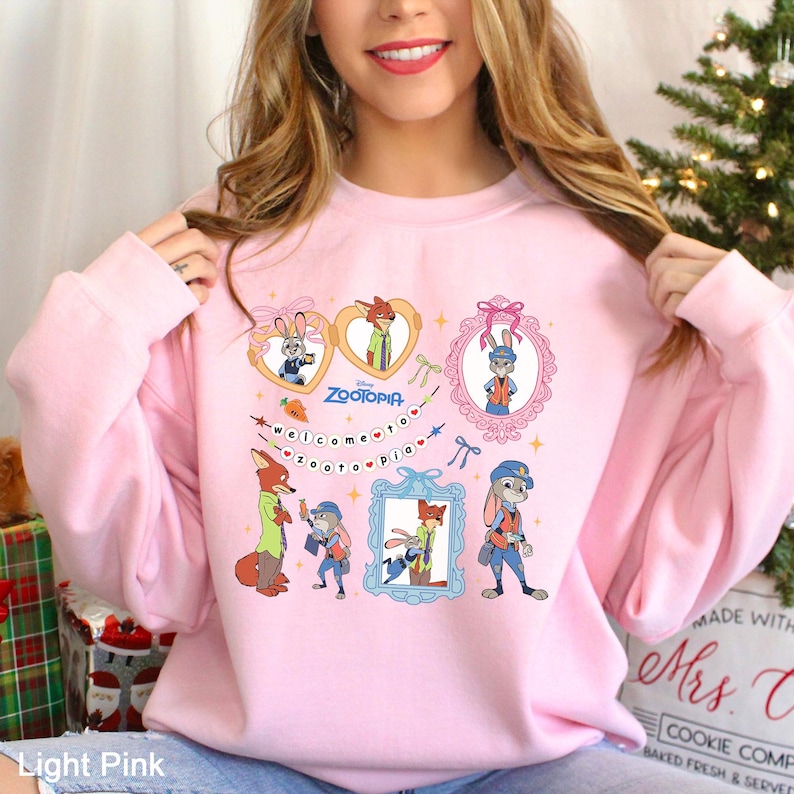 A woman wearing a pink sweatshirt with a collage of cartoon animal characters and a message.
