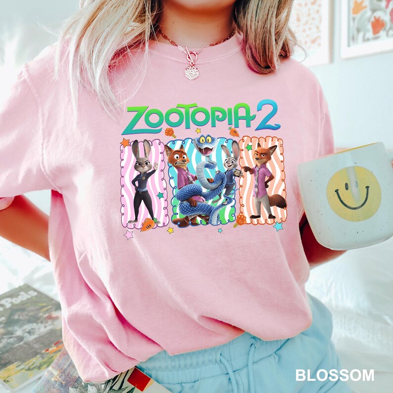 A person wearing a pink t-shirt with a cartoon character design and holding a coffee mug with a smiley face.