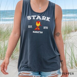 A person wearing a grey tank top with a graphic of a character from the Marvel Cinematic Universe, specifically Iron Man, printed on it.