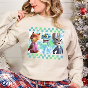 A woman wearing a white sweatshirt with a graphic design featuring three cartoon animal characters: a fox, a snake, and a rabbit.