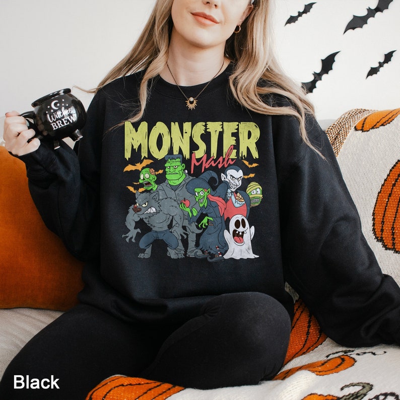 a woman sitting on a couch wearing a black monster sweatshirt