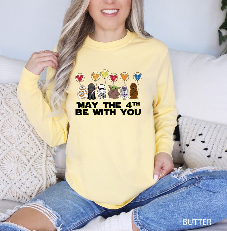 a woman sitting on a couch wearing a yellow shirt that says may the 4th be
