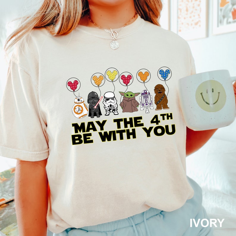 a woman wearing a star wars shirt holding a mug