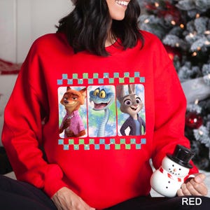 A woman wearing a red sweater with a graphic of three cartoon animal characters, including a fox, a snake, and a rabbit.