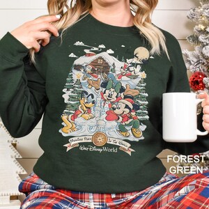 a woman holding a coffee mug in front of a christmas tree
