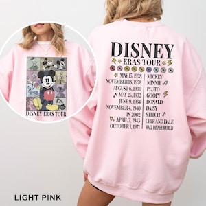 a woman wearing a pink disney sweatshirt with a picture of mickey mouse on it