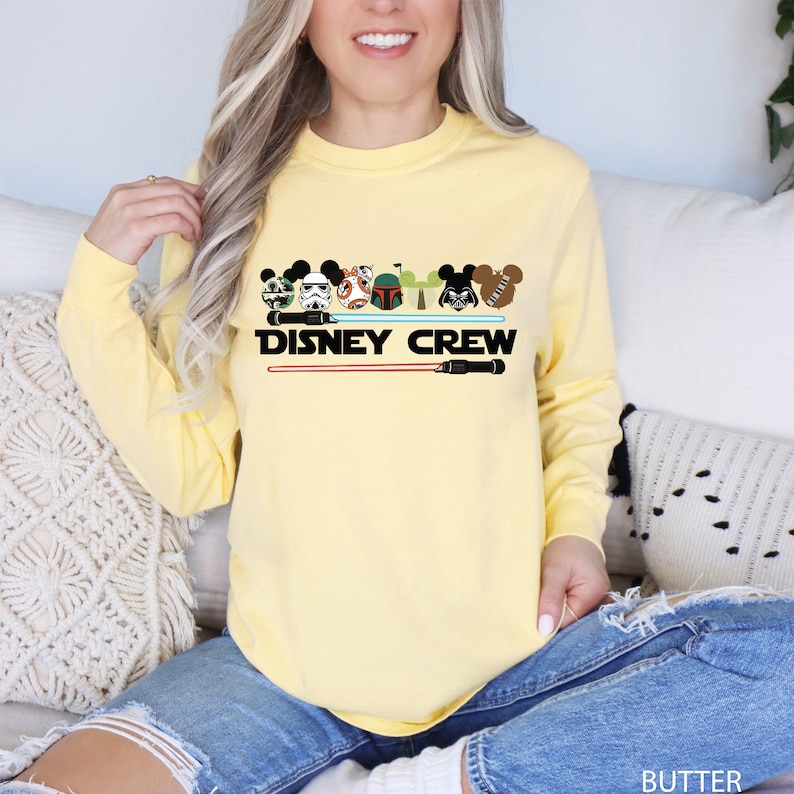 a woman sitting on a couch wearing a yellow disney crew shirt