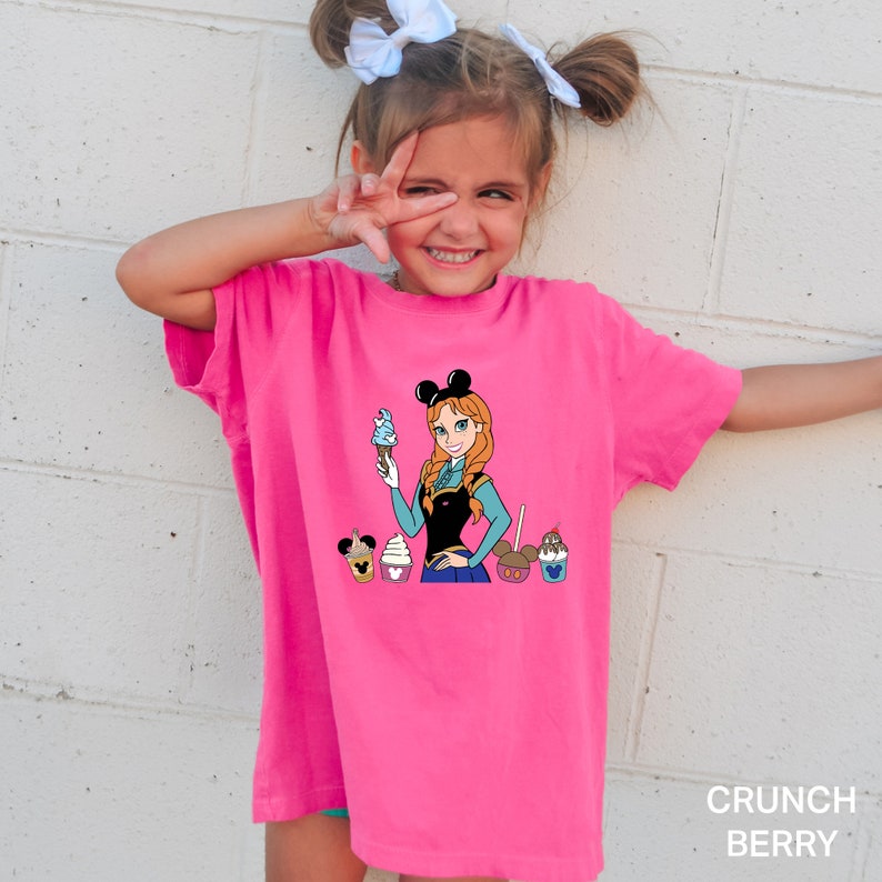 a little girl wearing a pink shirt with a cartoon character on it