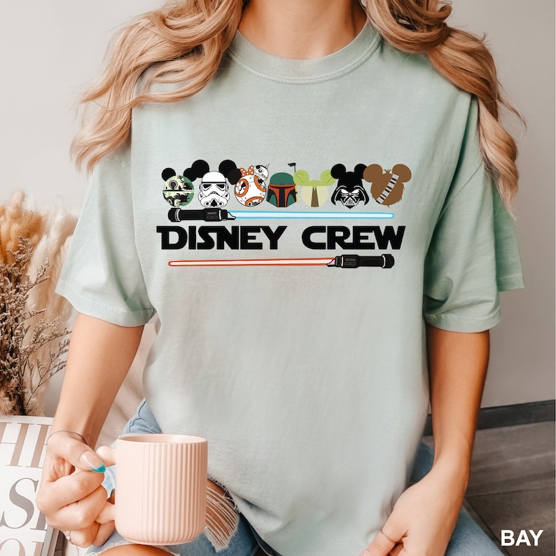 a woman is holding a coffee mug and wearing a disney crew shirtStar Wars Disney Crew Shirt, Comfort Colors Disney Shirt, Star Wars Family Shirt, Disney Star Wars Shirt, Disney Crew Shirt,