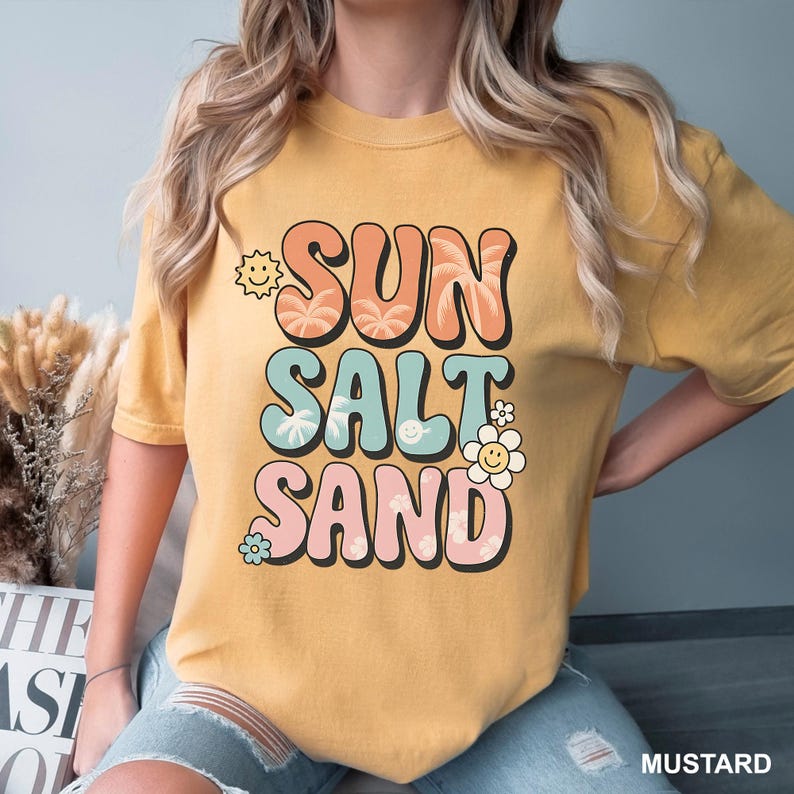 A woman wearing a yellow t-shirt with the text "SUN SALT SAND" printed on it.