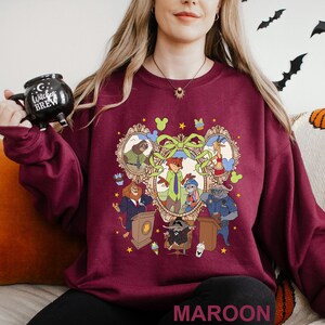 A woman wearing a maroon sweater with a graphic design featuring cartoon characters and various objects.