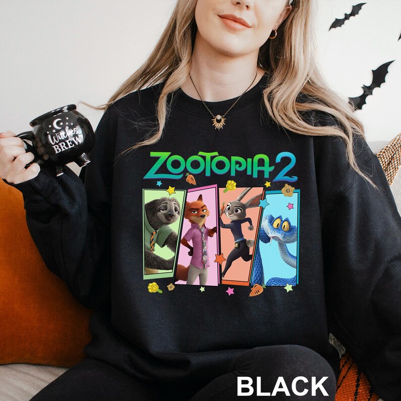 A woman wearing a black sweatshirt with a colorful graphic of the characters from the animated film "Zootopia 2" on it.