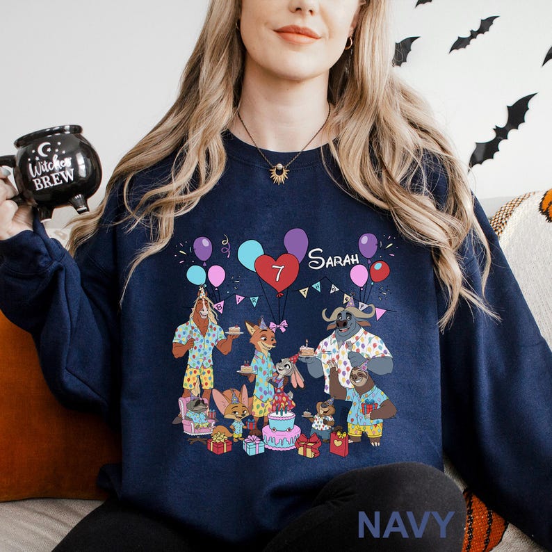 A woman wearing a navy blue sweatshirt with a graphic design of cartoon animals celebrating a birthday.