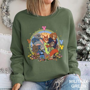 A woman wearing a green sweatshirt with a colorful graphic of cartoon characters from the Disney movie "Jurassic Park" on it.