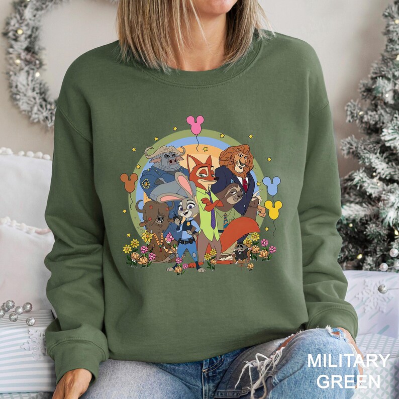 A woman wearing a green sweatshirt with a colorful graphic of cartoon characters from the Disney movie "Jurassic Park" on it.