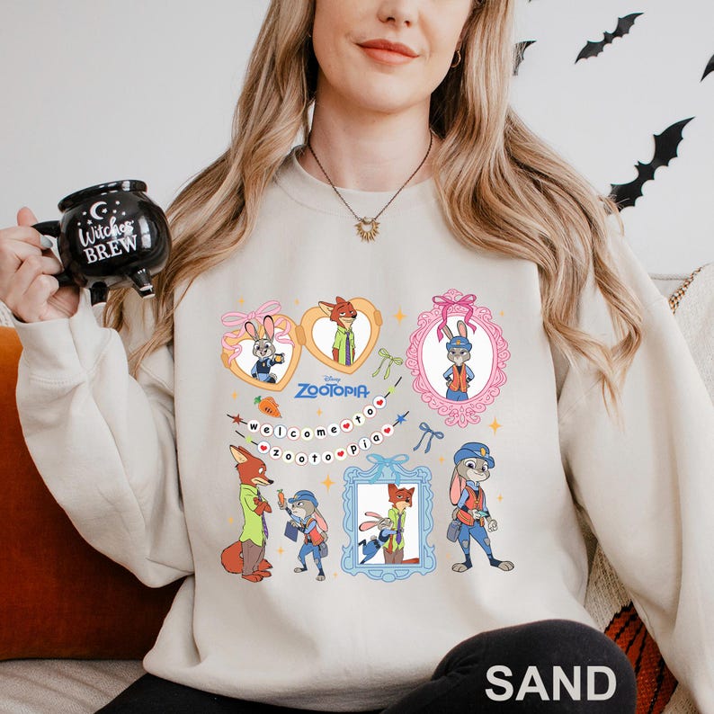 A woman wearing a white sweatshirt with a graphic of various cartoon characters from the movie "Zootopia" printed on it. She is holding a mug with the movie's title printed on it.