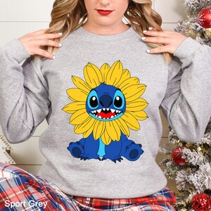 A woman wearing a gray sweatshirt with a cartoon character printed on it.