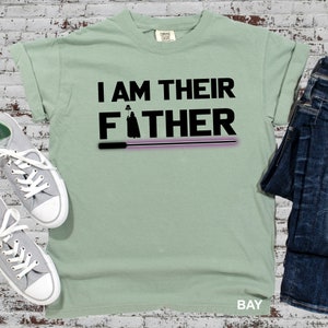 May include: A light green t-shirt with the text "I AM THEIR FATHER" in black. A silhouette of Darth Vader is above the word "FATHER" and a purple lightsaber is below the word "FATHER".