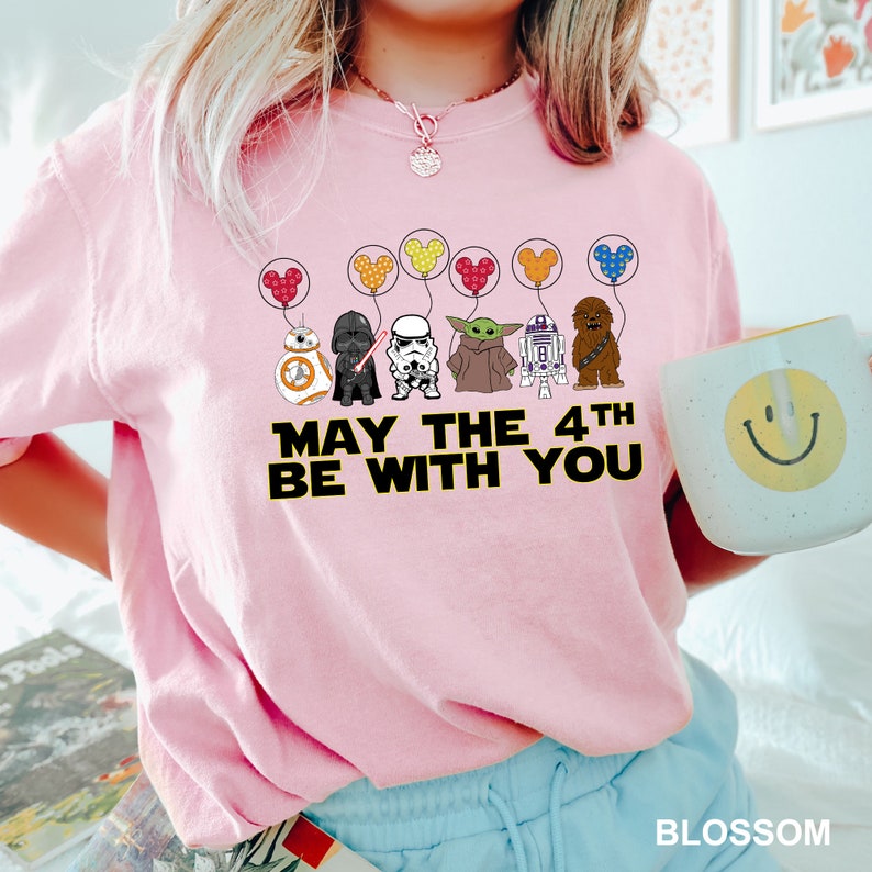 a woman wearing a pink shirt with star wars characters on it