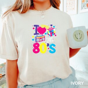 a woman holding a mug with the words i love the 80's on it