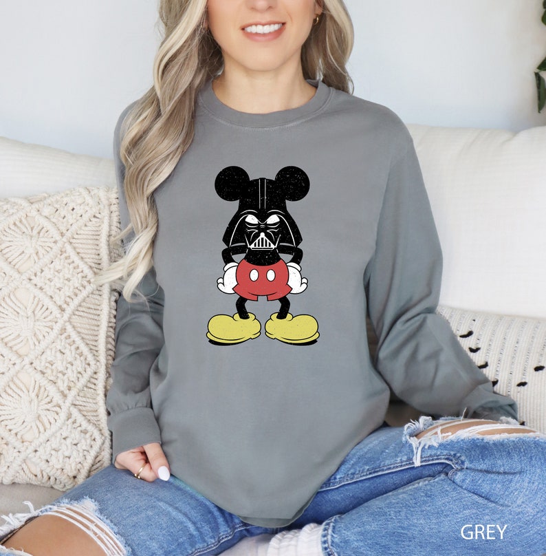 a woman sitting on a couch wearing a mickey mouse sweatshirt
