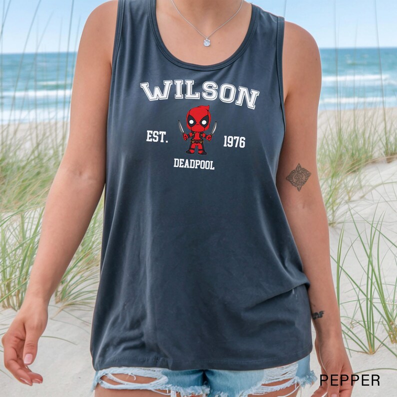 A person wearing a gray tank top with a graphic of a character from the Marvel Cinematic Universe, specifically Deadpool, printed on it.