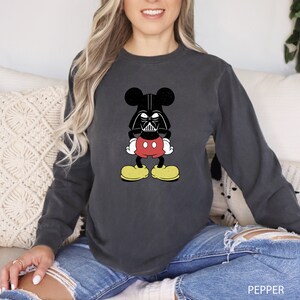 a woman sitting on a couch wearing a mickey mouse shirt