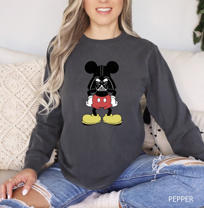 a woman sitting on a couch wearing a mickey mouse shirt