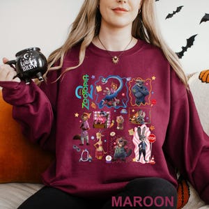 A woman wearing a maroon sweatshirt with a collage of colorful cartoon characters and various other images printed on it.