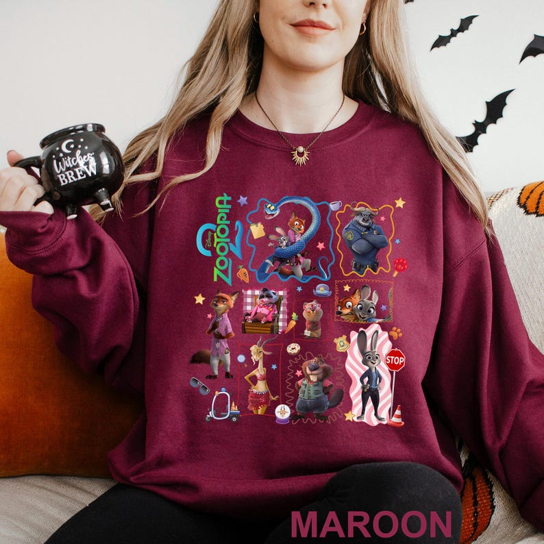 A woman wearing a maroon sweatshirt with a collage of colorful cartoon characters and various other images printed on it.