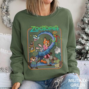 A woman wearing a green sweatshirt with a graphic of the characters from the animated film "Zootopia" on it.
