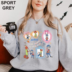 A woman wearing a grey sweatshirt with a graphic design featuring cartoon rabbit characters and various other cartoon-style elements.