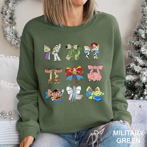 A woman wearing a green sweatshirt with a collage of cartoon characters printed on it.