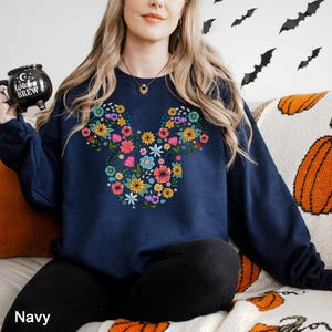 a woman sitting on a couch with a mickey mouse sweatshirt on