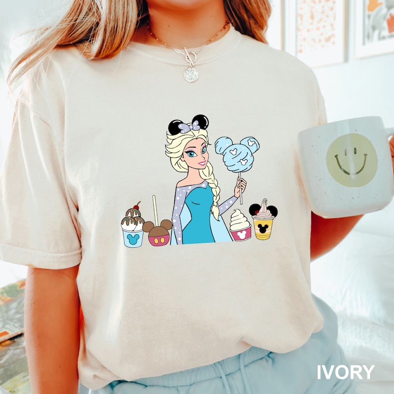 a woman holding a cup of coffee and a mickey mouse t - shirt Disney Princess Elsa Shirt, Comfort Colors Disney Shirt, Disney Family Shirt, Disney Frozen Shirt, Disney Princess Shirt,