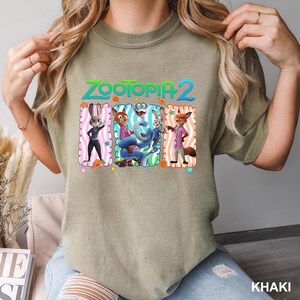 A person wearing a t-shirt with a graphic design featuring characters from the animated film "Zootopia 2".