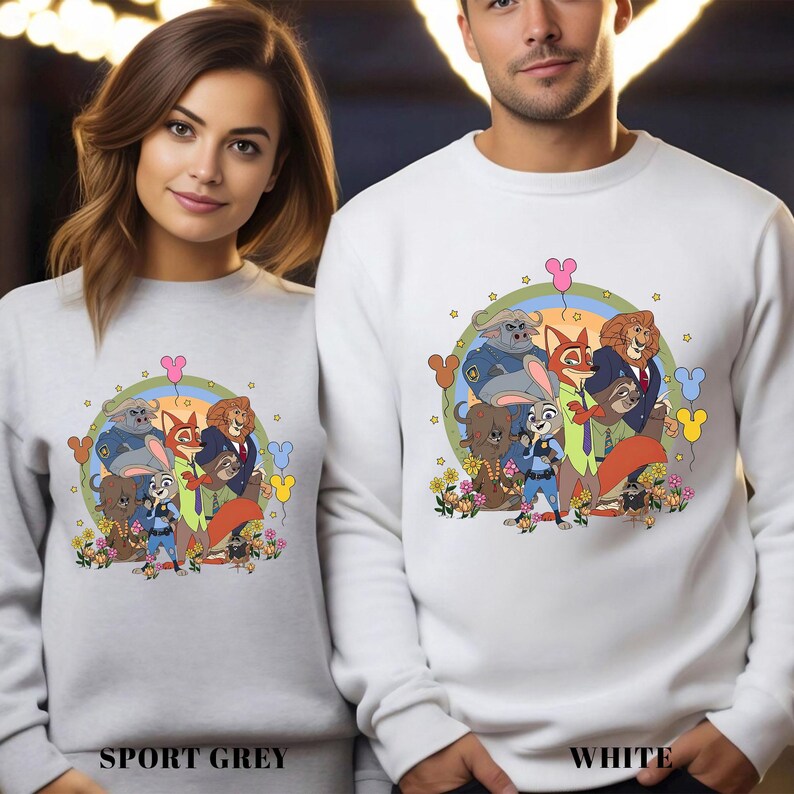 Two people wearing white sweatshirts with a colorful illustration of cartoon animals on them.