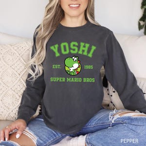 A woman wearing a black sweatshirt with a graphic of a green character and text printed on it.