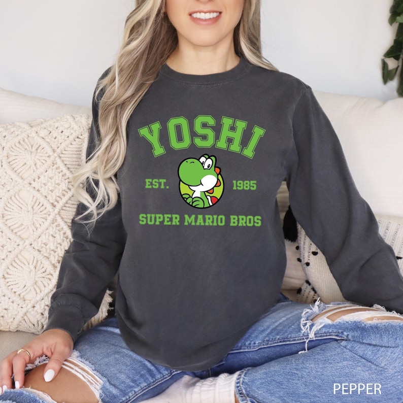 A woman wearing a black sweatshirt with a graphic of a green character and text printed on it.