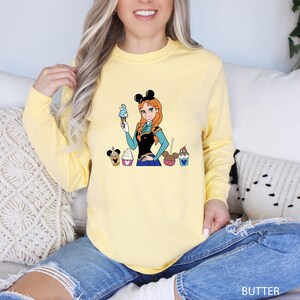 a woman sitting on a couch wearing a yellow shirt