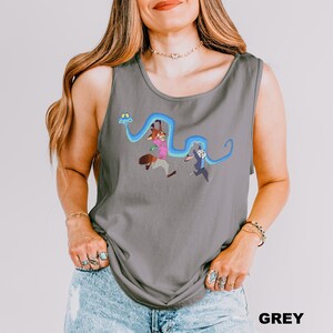 A woman wearing a gray tank top with a graphic design of cartoon characters and a snake.