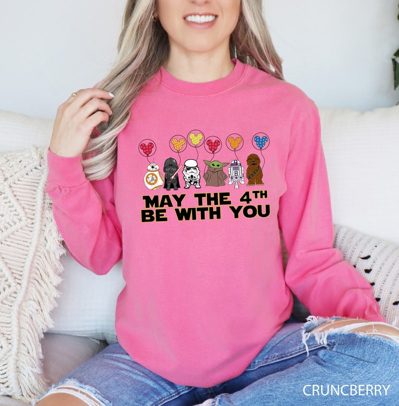 a woman sitting on a couch wearing a pink sweatshirt