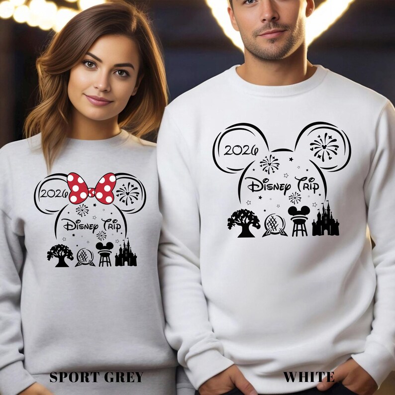 A woman and a man standing next to each other, both wearing white sweatshirts with a Disney-themed design.